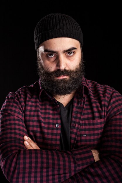 Long bearded man wearing a hat on black background in studio photo