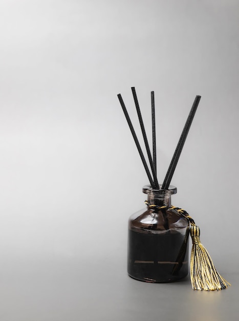 Long black fragrant sticks one by one In a luxury opaque glass bottle with essential oils to spread the fragrance gray background There is a text area