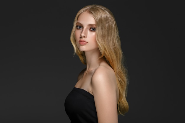 Long blonde hair model woman over black background film effect. Beauty concept. Studio shot.