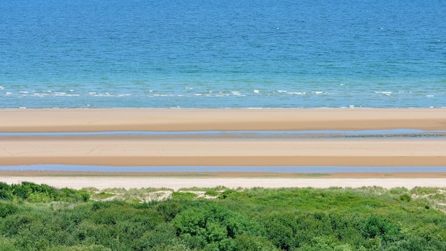 Long calm beach with blue cloudy sky.