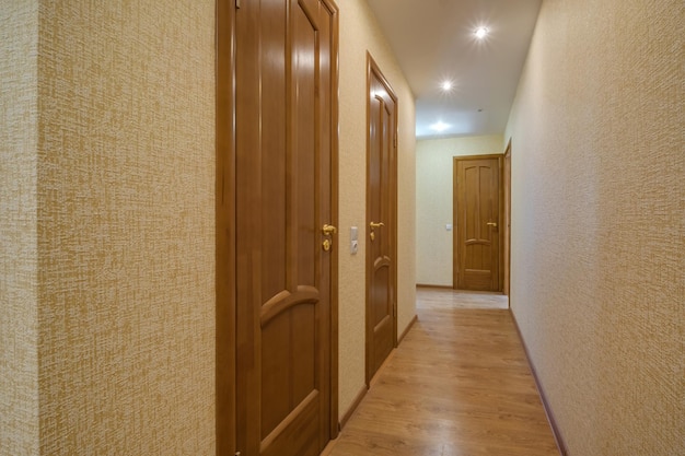 Long corridor in interior of entrance hall of modern apartments with doors cabinets shelves and a mirror