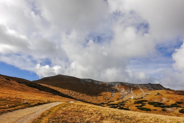 Long dirt road through a hilly landscape at the top from a mountain