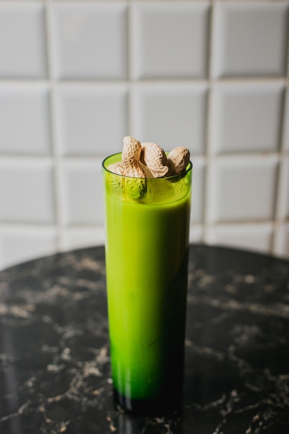 A long drink cocktail in a green highball glass garnished with peanuts