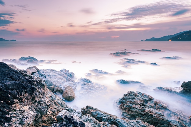 일몰 풍경 배경에서 바위와 극적인 하늘 바다의 긴 노출 이미지.