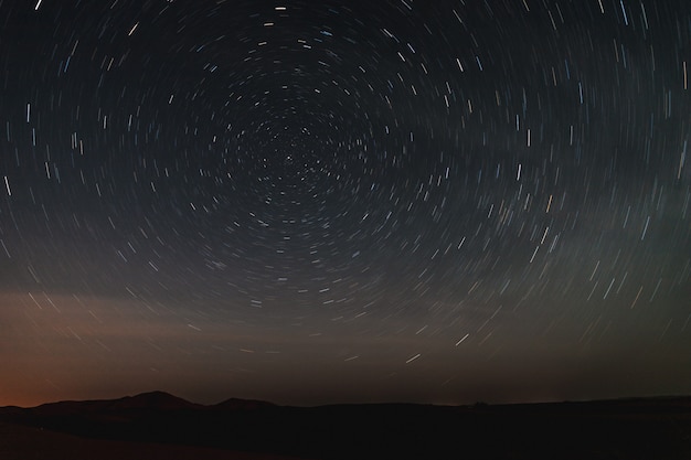 Long exposure photo of the sky in the sahara desert, looking star trails at night.