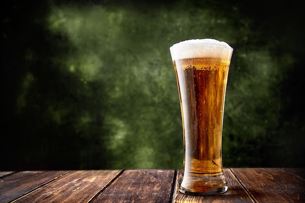 Photo long glass of beer on dark green background