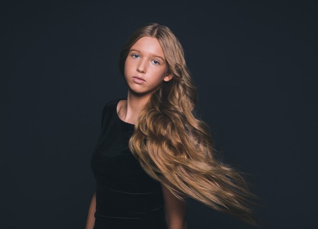 Long hair beauty girl healthy curly long hairstyle blonde in black dress. Studio shot.