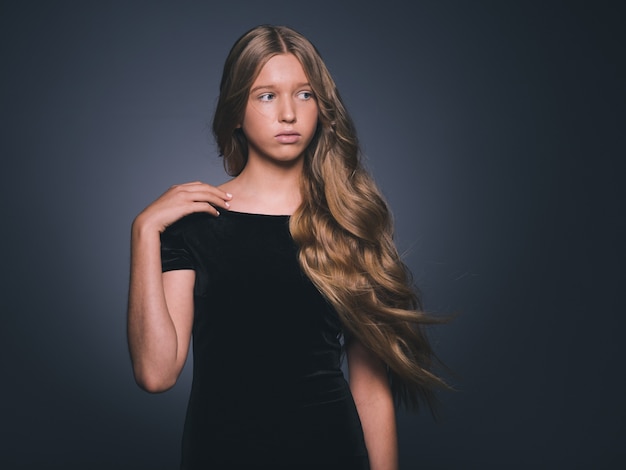 Capelli lunghi bellezza ragazza bionda acconciatura lunga riccia sana in vestito nero. colpo dello studio.