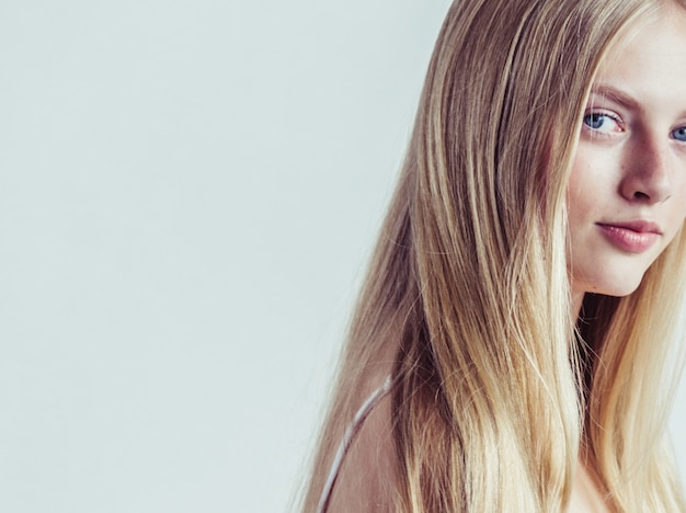 Long hair blonde young model. Beauty girl with curly perfect hairstyle. Studio shot.