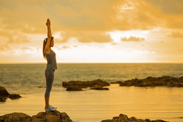 long hair good shape asian woman playing yoga exercise on rock at twilight light