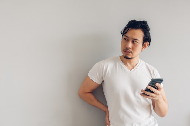 Long hair man in white casual t-shirt is using smartphone.