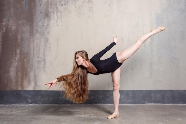 Photo long haired artist woman dancing near gray wall. studio shot