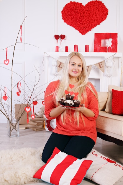 Long-haired blonde holding a festive dessert for Valentines Day