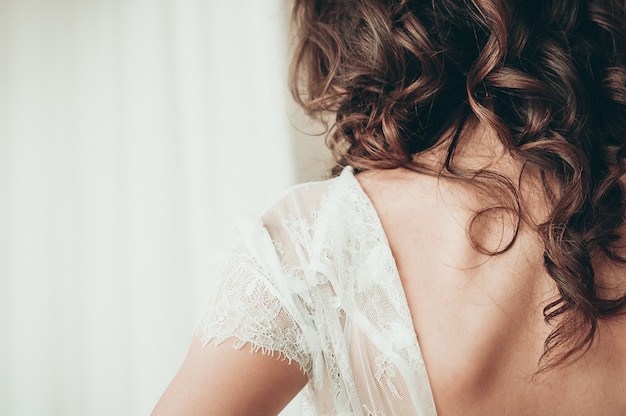 long haired brunette bride in unbuttoned white dress a closeup view from the back