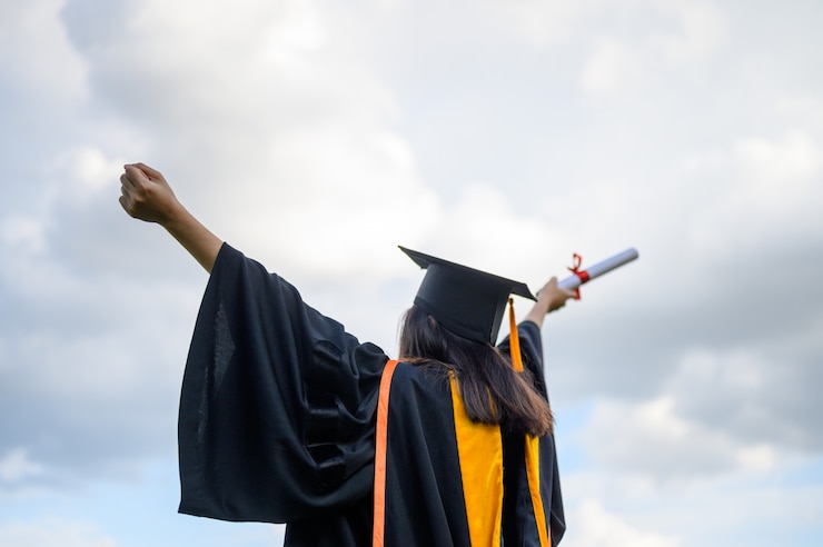 Photo long haired female students wearing black ruffle dresses expressing joy on graduation at the university.