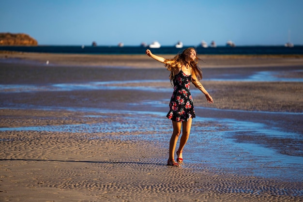 Long-haired girl in black dress dances on beach in coral bay,\
australia at sunset, romantic sunset