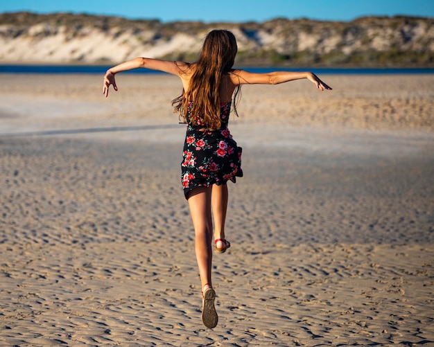 Long-haired girl in black dress dances on beach in coral bay,\
australia at sunset, romantic sunset