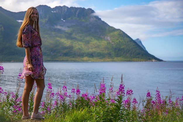 a long-haired girl in a colourful dress enjoys the sunny weather on the island of senja, norway