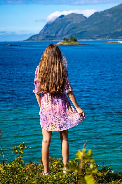 カラフルなドレスを着た長髪の少女がノルウェーのセンジャ島の海辺を歩く