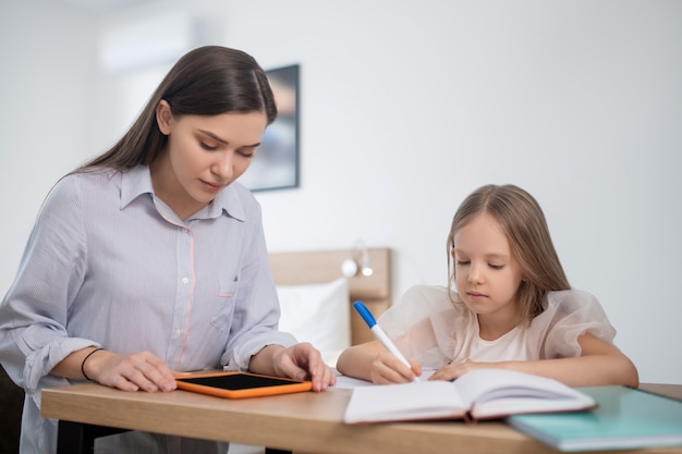 A long-haired girl studying at home and looking involved