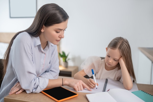 A long-haired girl studying at home and looking involved