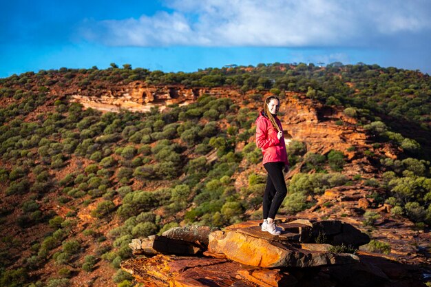 long-haired girl walks along a ridge on the red rocks of kalbarri national park in western australia