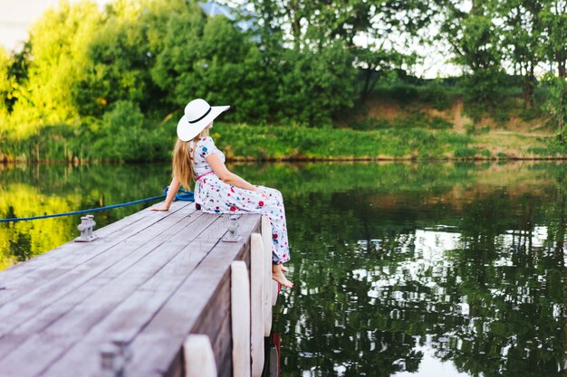 Una donna dai capelli lunghi con un cappello bianco e un bellissimo abito lungo