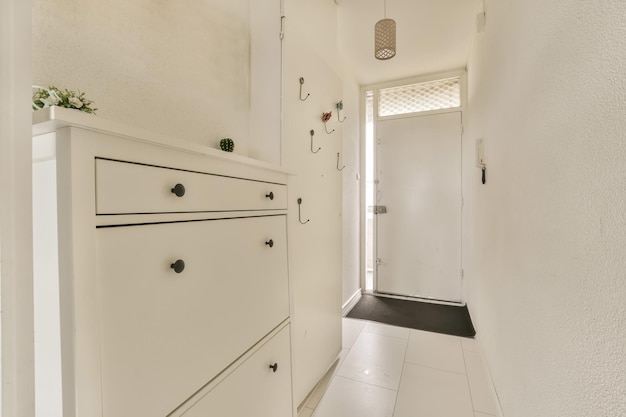 A long hallway with white cabinets and a white door