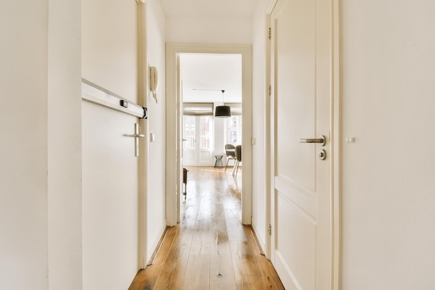 Photo a long hallway with white walls and wood flooring on either side by side leading to the living room