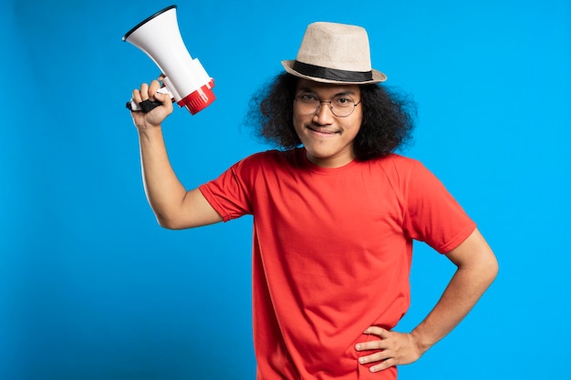 Long har man smiling and standing over blue background holding megaphone