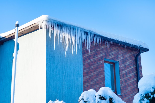 Long icicles on building roof in winter day