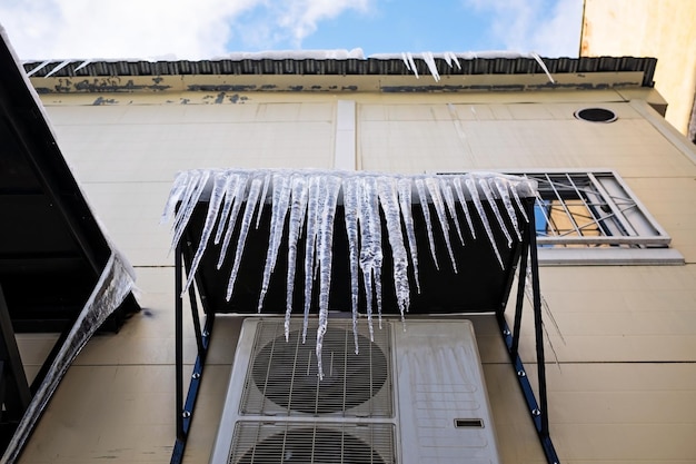 Foto lunghi ghiaccioli cadono dal tetto in inverno e all'inizio della primavera