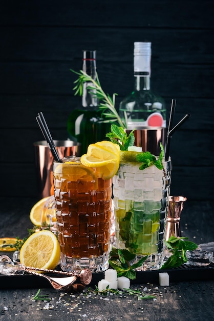 Cocktail alcolici long island e mojito su uno sfondo di legno nero