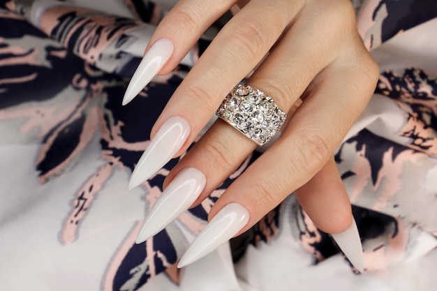 Long light manicure with jewelry on a womans hand