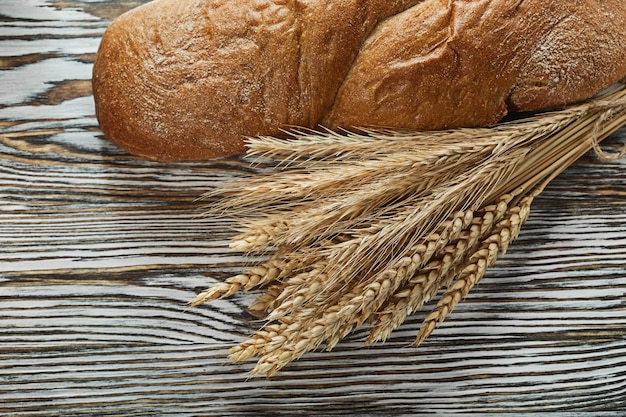 Long loaf wheat ears on wooden surface