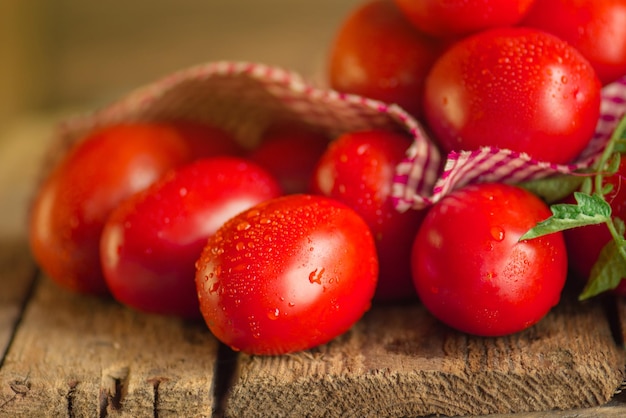 Длинные помидоры сливы с клетчатой красной салфеткой на деревянном столе Куча свежих помидоров