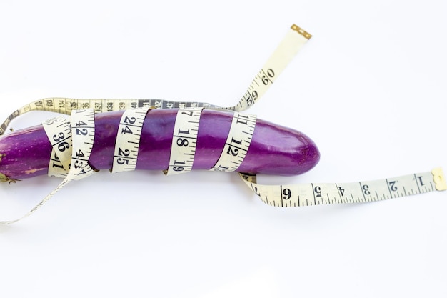 Long purple eggplant wrapped in measuring tape on white background