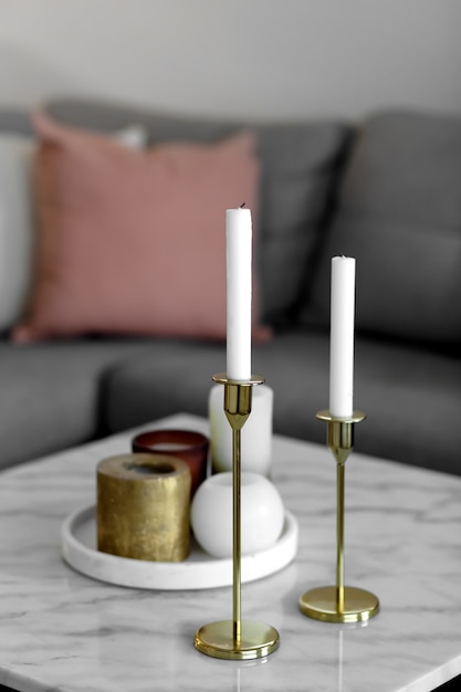 Long and round candles in gold candlesticks on the table interior in the house decoration of the apa...