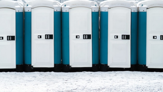 Длинный ряд передвижных туалетов снаружи на заснеженной земле. биотуалеты на открытом воздухе.