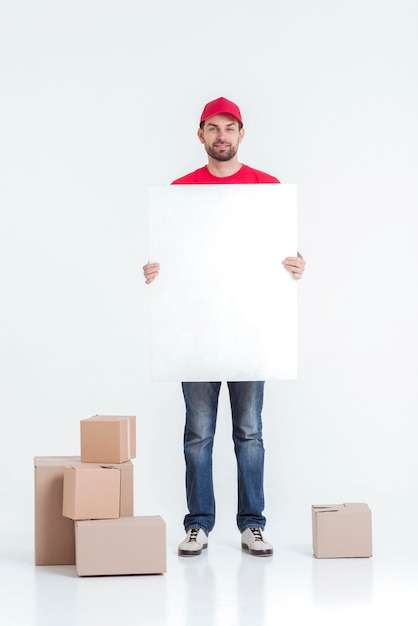 Photo long shot of courier surrounded by boxes holding an empty board