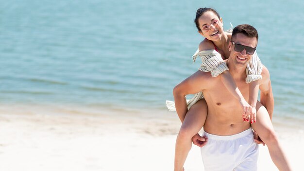 Colpo lungo delle coppie felici alla spiaggia