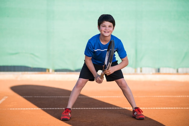 Photo long shot kid playing tennis