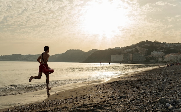 Foto bagnino del tiro lungo che corre sulla spiaggia