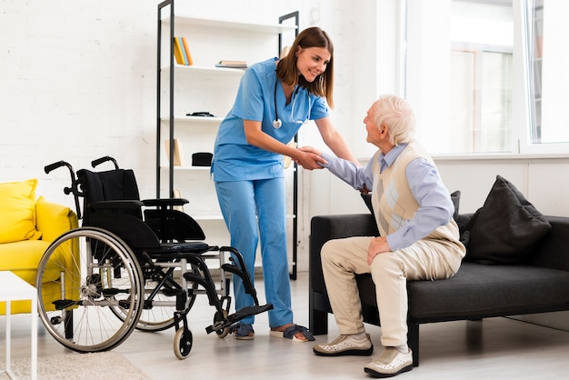 Photo long shot nurse helping old man getting up