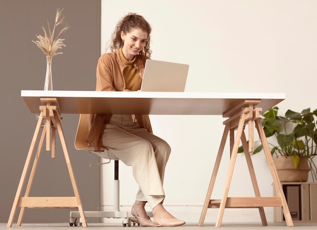 Photo long shot of person sitting and working on laptop