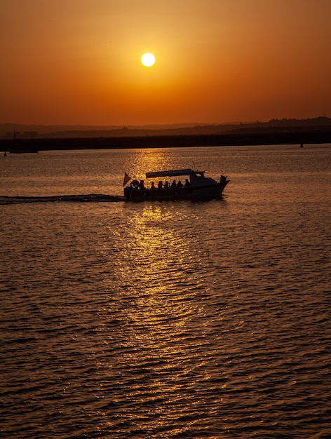 long shot van een boot die bij zonsondergang snel een Spaans strand oversteekt