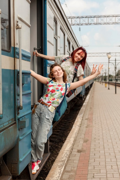 Long shot women hanging off train doorway