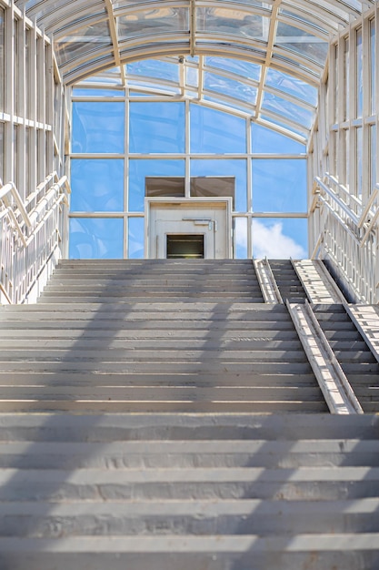 Длинная лестница к надземному пешеходному переходу белого цвета в яркий солнечный день