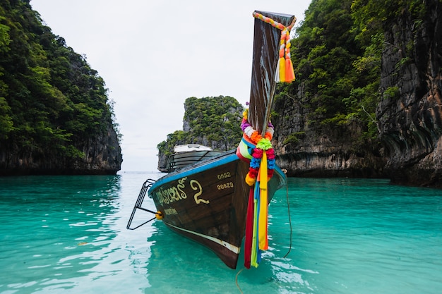 Long-tail boat floating in transparent water of phi-phi island, maya bay, the paradise island in thailandia.