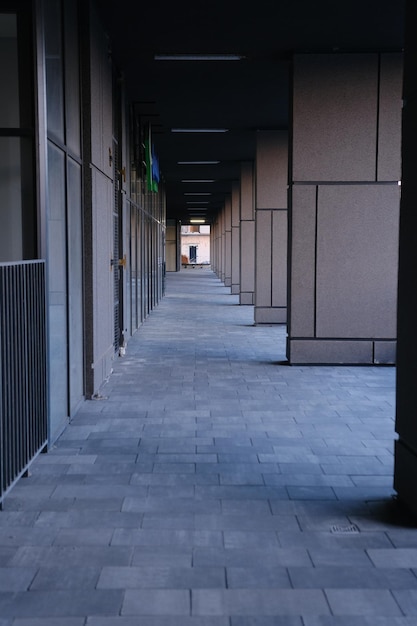 Long tunnel with columns and metal fance in modern city architecture with low lights and grey colors with tile on the frloor